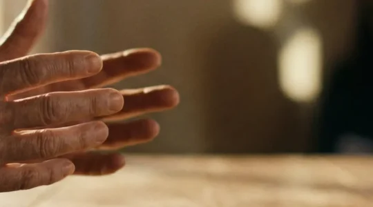 Mains de conteur esquissant un geste narratif face à une lumière dorée, symbolisant le pouvoir du storytelling de marque pour convertir des prospects froids